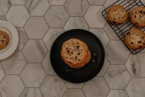 Stack of chocolate chip cookie sitting on plate surrounded by cookies Stock Photos