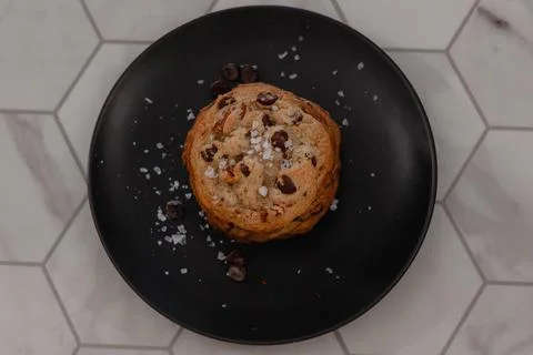 Stack of chocolate chip cookies covered in salt on black plate 스톡 사진