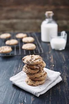 Stack of chocolate chip cookies with milk in background on wooden table Stock Photos