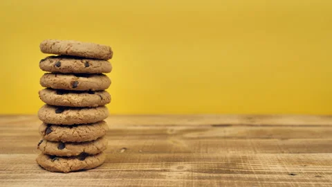 A stack of chocolate chip cookies sprout on a wooden table with a yellow Stock Footage 166465759