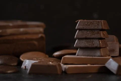 Stack of chocolate cubes and dark chocolate bars on black background. Desse.. 写真素材