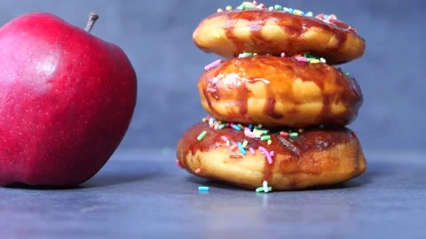 Stack of chocolate donuts and apple on table Stock Footage 144584398