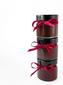 Stack of chocolate jars with red ribbons on white background Foto stock