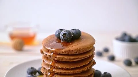 Stack of chocolate pancakes with blueberries and syrup on a plate Stock Photos
