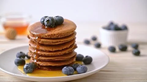 Stack of chocolate pancakes with blueberries and syrup on a white plate Stock Photos