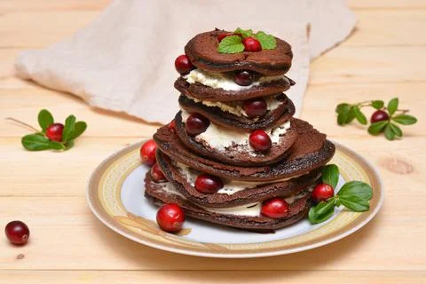 A stack of chocolate pancakes with cranberries on a plate close-up Stock Photos