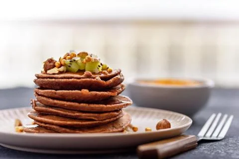 Stack chocolate pancakes with kiwi, hazelnut, maple syrup on plate with fork  Stock Photos