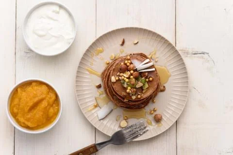 Stack of chocolate pancakes with nuts, honey, coconut flakes, jam and sour cr Stock Photos