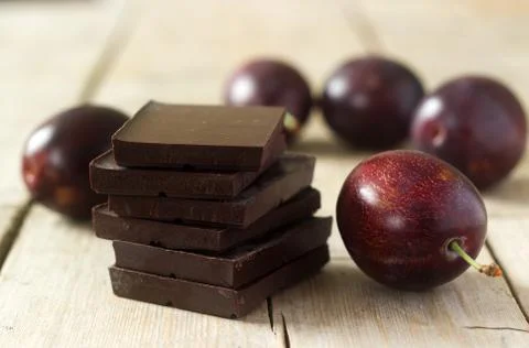 A stack of chocolate slices and plums on a wooden table. Rustic style, select Stock Photos