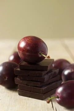 A stack of chocolate slices and plums on a wooden table. Rustic style, select Stock-Fotos