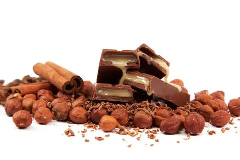 Stack of chocolate tiles with hazelnuts and cinnamon sticks on a white backgr Stock Photos