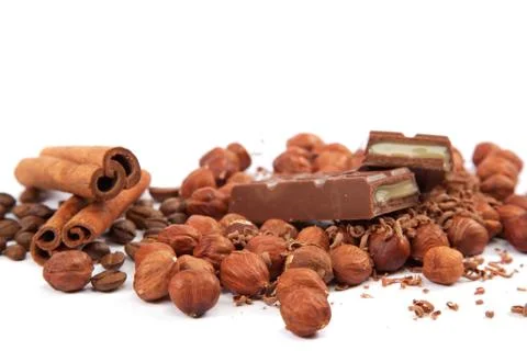 Stack of chocolate tiles with hazelnuts and cinnamon sticks on a white backgr Stock Photos