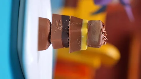 Stack of chocolates with colorful layers on white plate, slow motion video .. Stock Footage 332627004