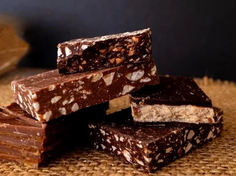 A stack of chocolates of different flavours on a rustic dark background. Stock Photos