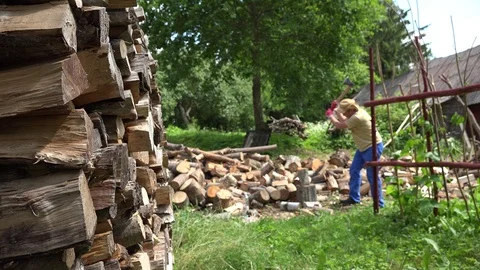Stack of chopped wood and blurred farmer man prepare firewood in yard. 4K Vídeo Stock 90372478
