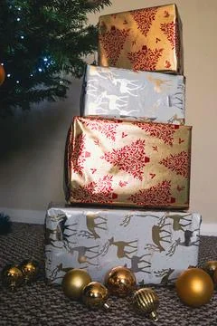 Stack of Christmas Presents Wrapped in Festive Holiday Paper Under Tree Stock Photos