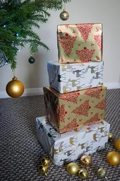 Stack of Christmas Presents Wrapped in Festive Holiday Paper Under Tree Stock Photos