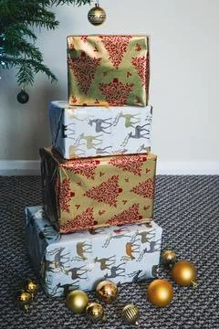Stack of Christmas Presents Wrapped in Festive Holiday Paper Under Tree Stock Photos