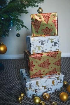 Stack of Christmas Presents Wrapped in Festive Holiday Paper Under Tree Stock Photos