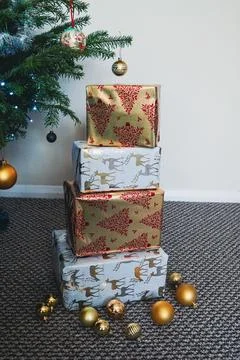 Stack of Christmas Presents Wrapped in Festive Holiday Paper Under Tree Stock Photos