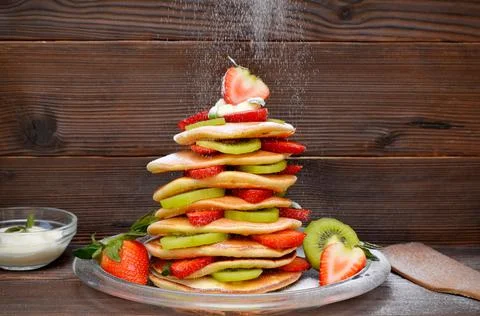 A stack of christmas tree pancakes and dripping powdered sugar on wooden back Stock Photos