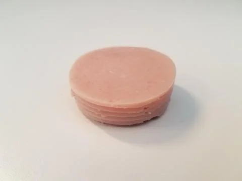Stack of circular pink ham meat on white surface Stockfoto's