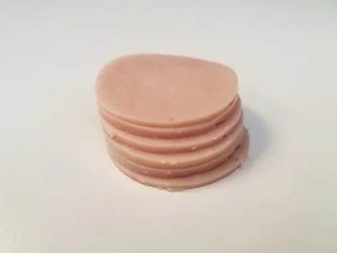Stack of circular pink ham meat on white surface Stockfoto's