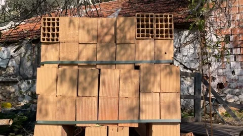Stack of clay bricks against rustic building background with shadows from n.. Stock Footage 328717634