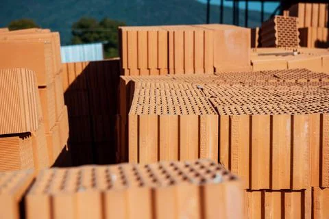 Stack of clay orange bricks on building site. Stock Photos