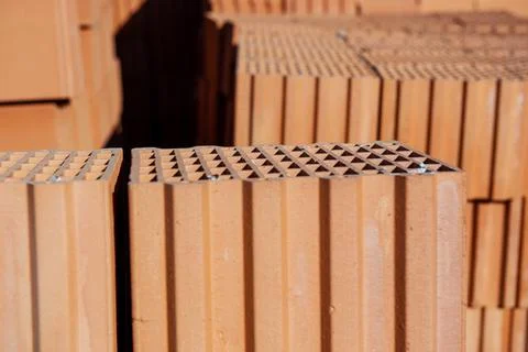 Stack of clay orange bricks on building site. Stock Photos