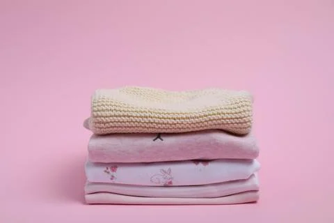 Stack of clean baby clothes on pink background 스톡 사진