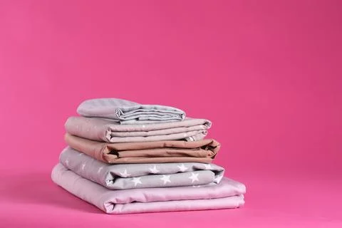 Stack of clean bed sheets on pink background 스톡 사진