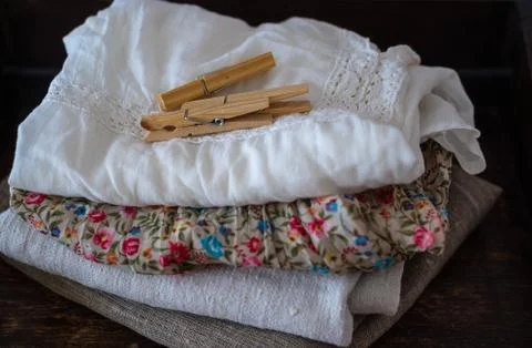 Stack of clean clothes and linen towels, clothespins on table Stock Photos