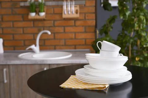 Stack of clean dishes and cups on table against blurred background. Space for Stock Photos