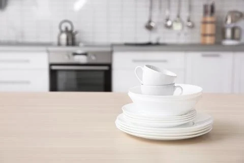Stack of clean dishes and cups on table against blurred background. Space for Stock Photos