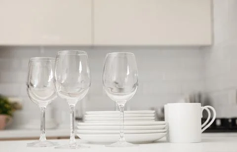 Stack of clean dishes, glasses and cups on table in kitchen Stock Photos