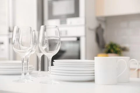 Stack of clean dishes, glasses and cups on table in kitchen Stock Photos