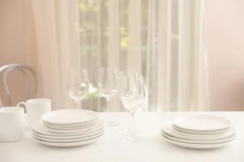 Stack of clean dishes, glasses and cups on table in kitchen Stock Photos