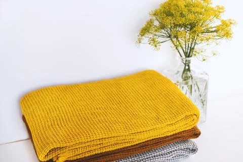 Stack of clean dry towels and vase with plants on table Stock Photos