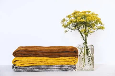 Stack of clean dry towels and vase with plants on table Stock Photos