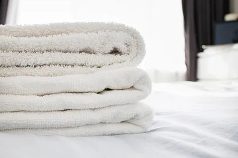 Stack of clean fluffy white towels on the bed Stock Photos