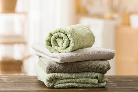 Stack of clean folded and rolled towels in various shades of green and gray o Stock Photos