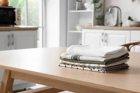 Stack of clean kitchen towels and dishcloths on wooden table in modern home k Stock Photos