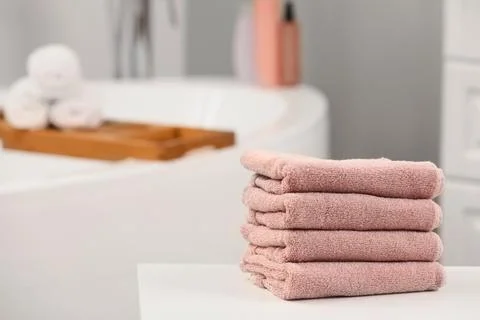 Stack of clean pink terry cloth towels on white bathroom countertop with bath Stock Photos