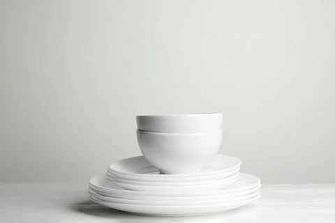 Stack of clean plates and bowls on wooden table against white background. Spa 스톡 사진