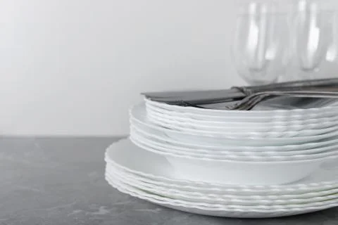 Stack of clean plates with forks, knives and glasses for serving on stone tab Foto stock