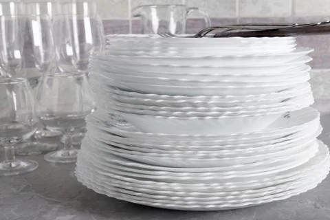 Stack of clean plates with forks, knives and glasses for serving Foto stock