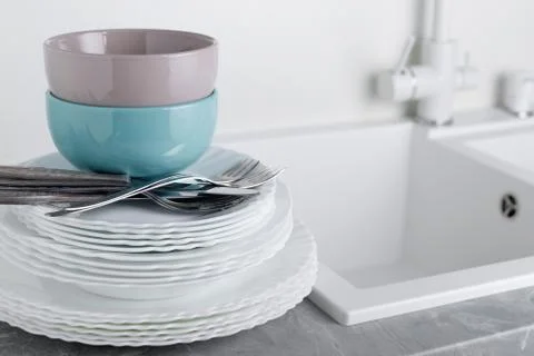 Stack of clean plates with forks, knives and glasses for serving on stone tab Stock Photos