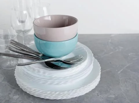 Stack of clean plates with forks, knives and glasses for serving on stone tab Stock Photos
