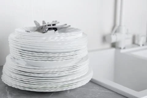 Stack of clean plates with forks, knives and glasses for serving Stock Photos